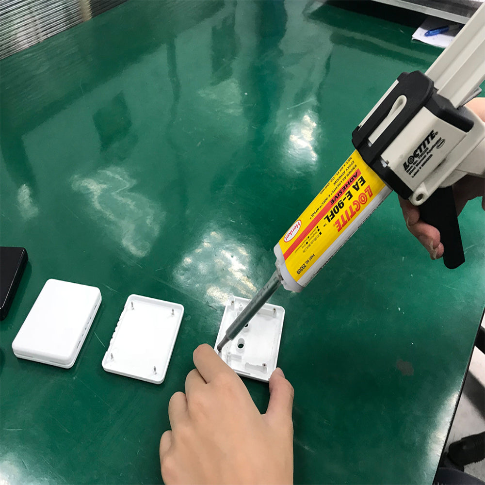 Applying Henkel Loctite EA E-90FL Hysol flexible grey epoxy adhesive to a plastic housing using a dual cartridge applicator gun.