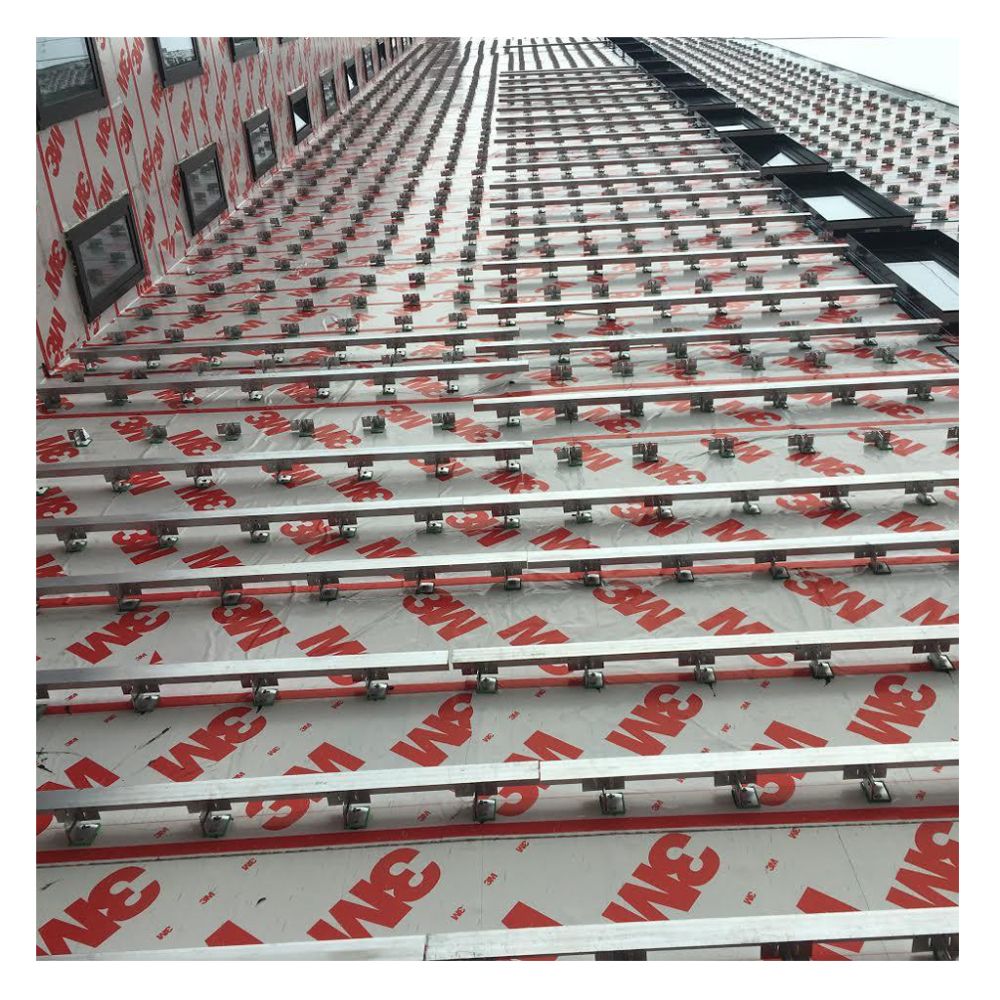 Large scale application of 3M 3015VP vapour permeable barrier membrane on a commercial building exterior, shown behind metal cladding support brackets.