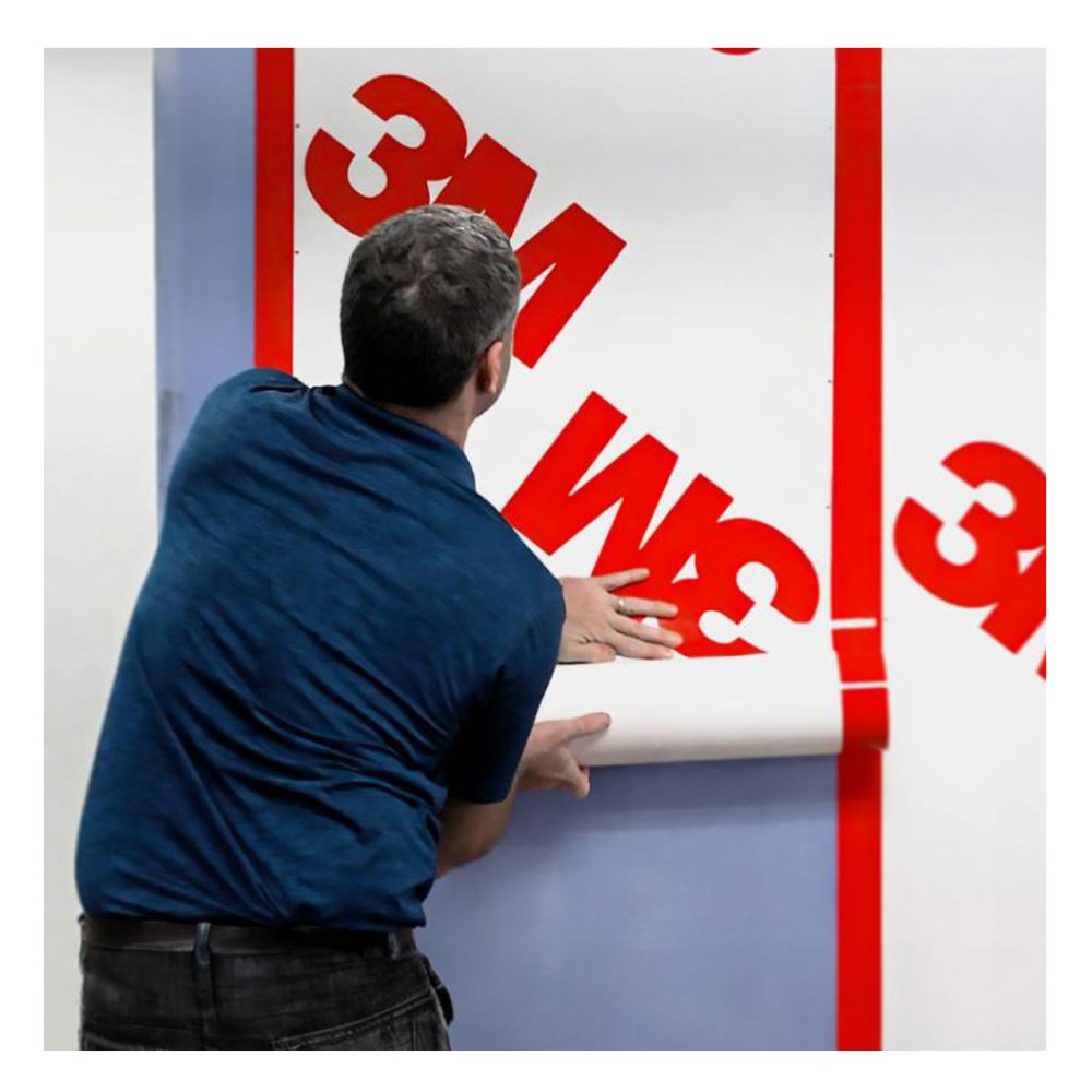 Professional installer applying a vertical strip of 3M 3015VP 30-inch wide vapour permeable membrane to a building substrate.