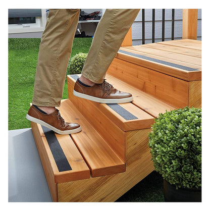 Person wearing brown leather shoes walking up wooden outdoor stairs installed with black 3M Safety-Walk anti-slip tread strips