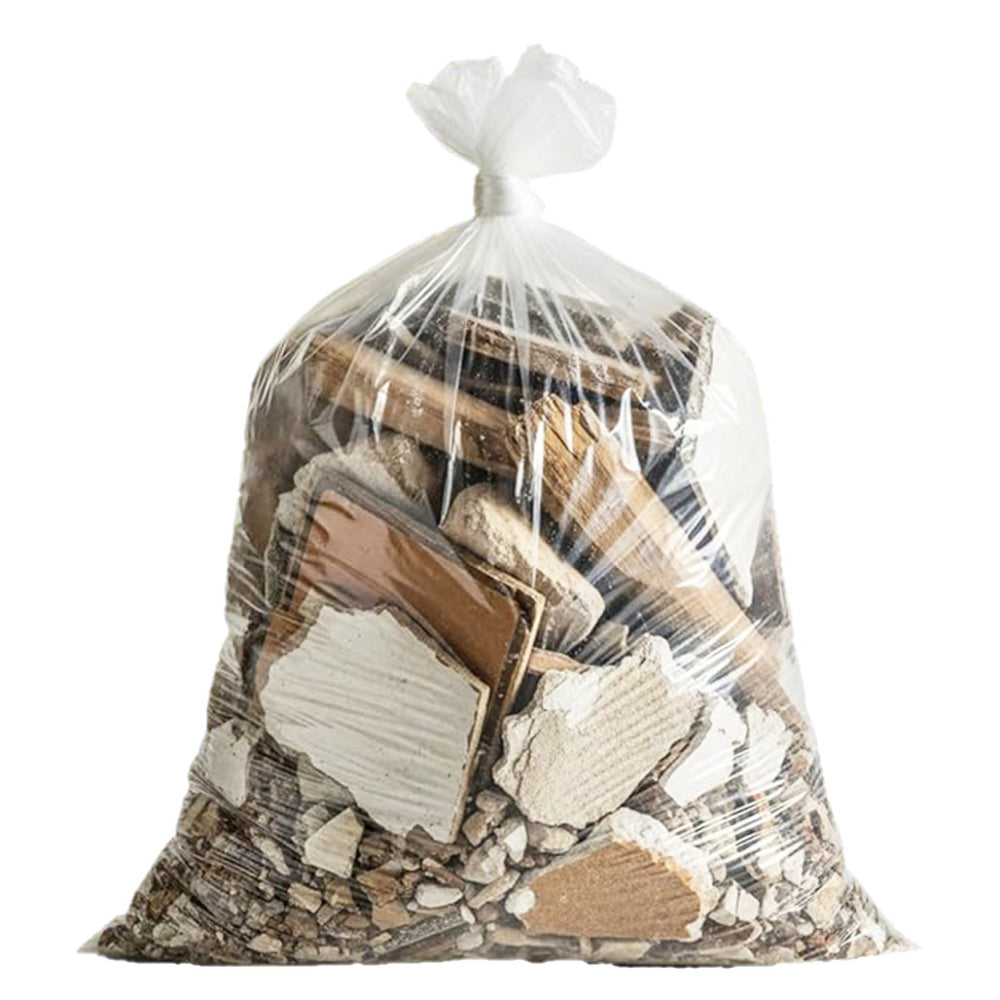 A heavy-duty clear contractor trash bag tied at the top and filled with construction demolition debris including broken drywall chunks, wood scraps, and concrete rubble isolated on a white background