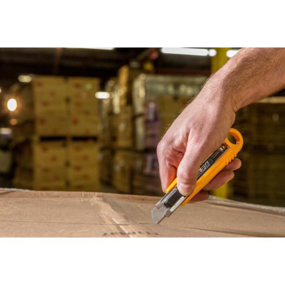 Hand slicing open a cardboard box with an OLFA safety utility knife in a warehouse
