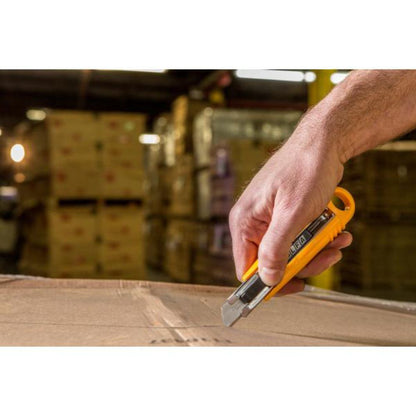 Hand slicing open a cardboard box with an OLFA safety utility knife in a warehouse