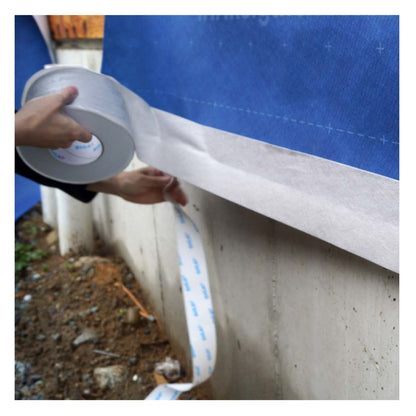 Application of an extra-wide 9-inch roll of Fentrim 430 grey joint sealing tape to a concrete foundation for a robust, airtight exterior seal.