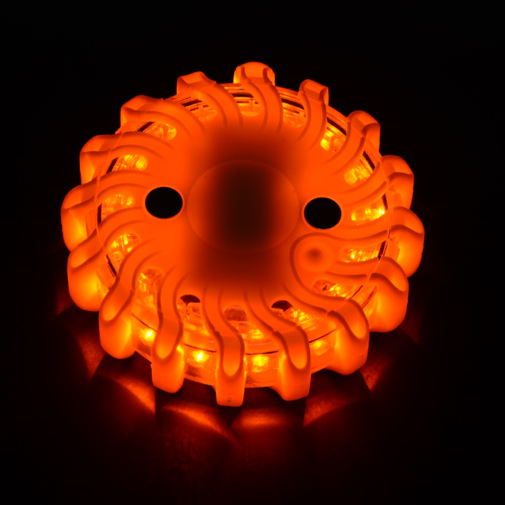 LEO orange LED safety flare illuminated in the dark demonstrating high-visibility 360-degree emergency lighting for traffic control.