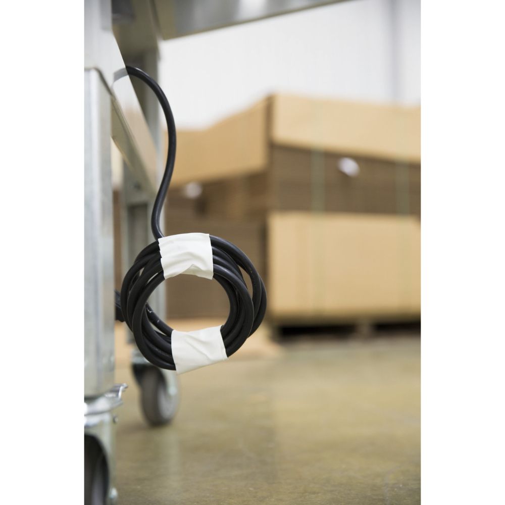 Coiled black power cable secured with white industrial masking tape in a warehouse.