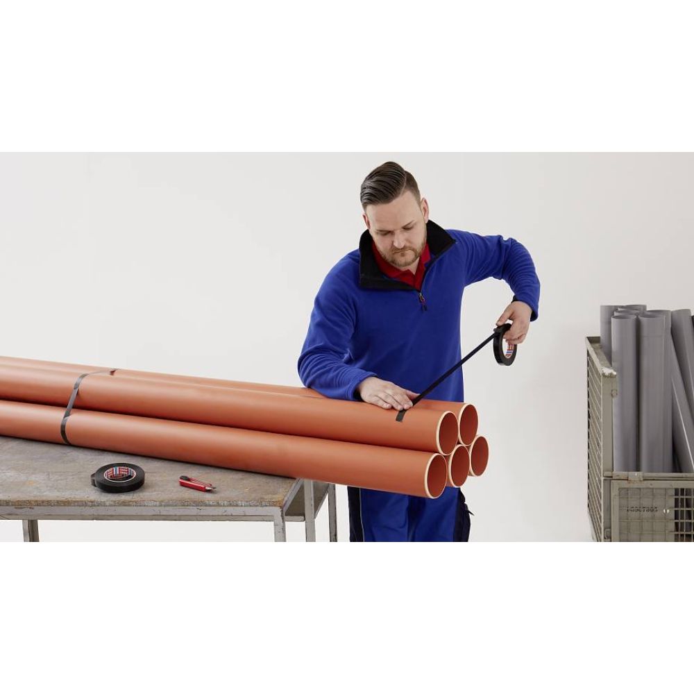 Worker Bundling PVC Pipes with Black Medium Duty Strapping Tape  4288