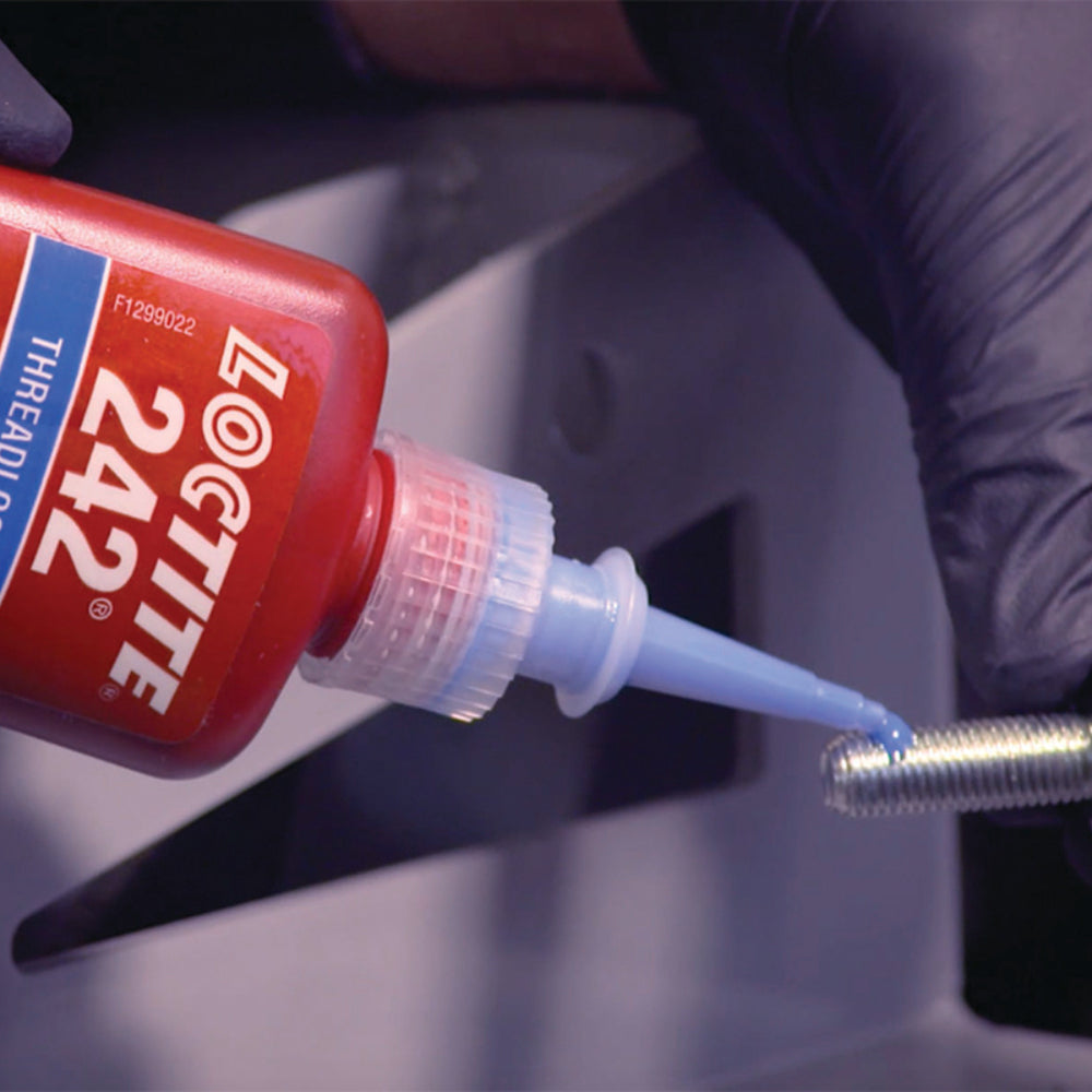 Gloved hands applying Loctite 242 blue medium strength threadlocker to metal bolt threads using precision tip, showing correct application technique for removable fastener locking
