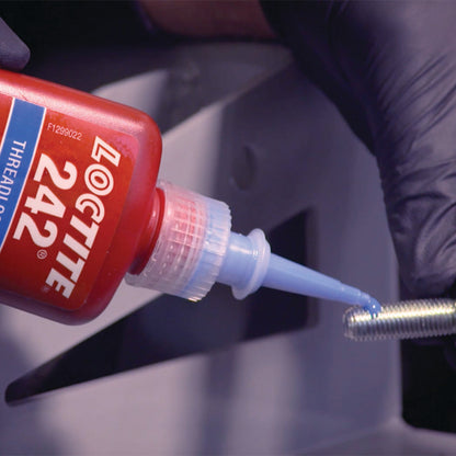 Gloved hands applying Loctite 242 blue medium strength threadlocker to metal bolt threads using precision tip, showing correct application technique for removable fastener locking