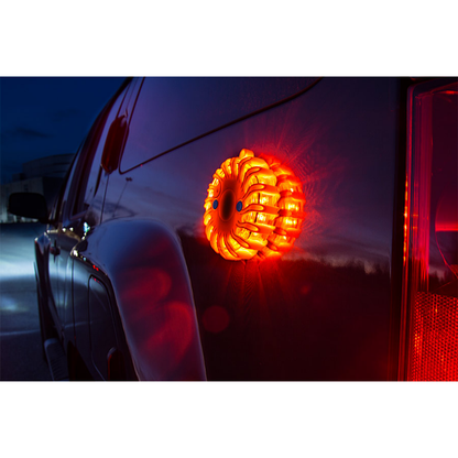 LEO orange LED road flare magnetically attached to the rear side of a vehicle at night, providing a bright warning signal for roadside safety.