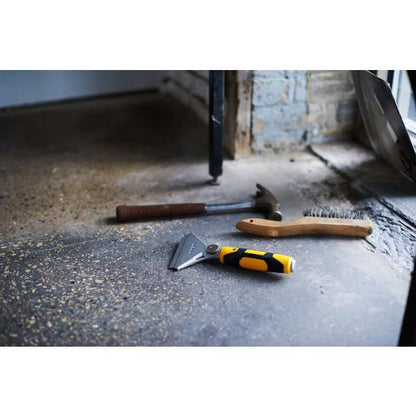 Olfa heavy duty scraper with yellow black handle placed on concrete floor beside hammer and brush
