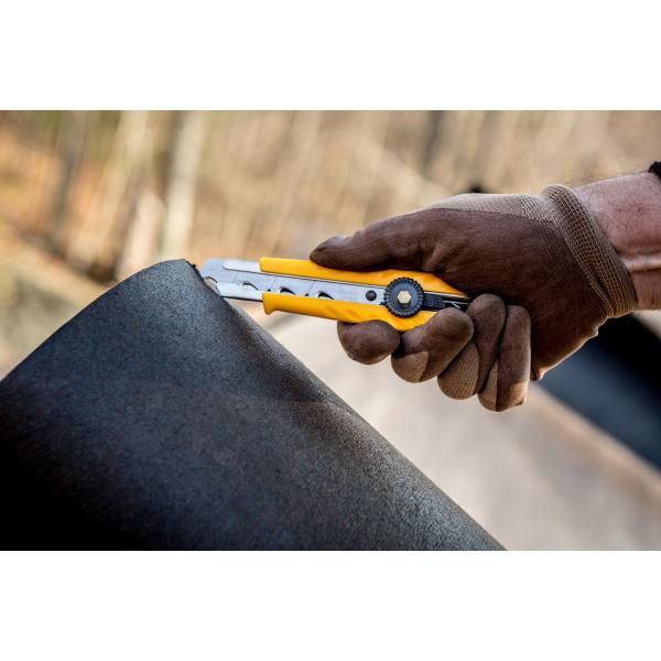 Worker using an OLFA L-1 heavy duty utility knife with a secure ratchet lock to smoothly slice through a thick black rubber sheet