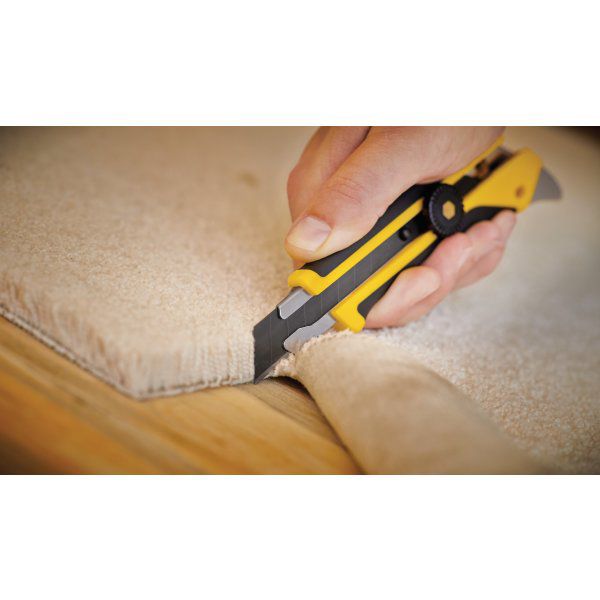 Tradesman using an OLFA L-5 heavy duty knife to cleanly slice through the edge of a beige textured carpet