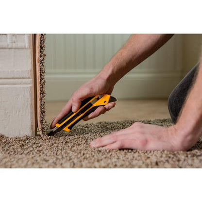 Close up view of a worker using a yellow and black OLFA utility knife to precisely cut heavy duty asphalt roofing shingles