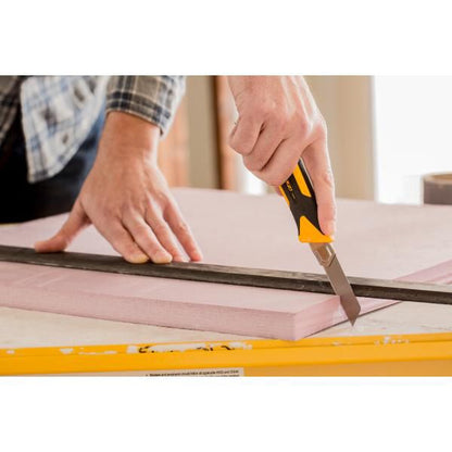 Precision cutting of a pink rigid foam insulation board with an OLFA utility knife guided along a straight edge ruler