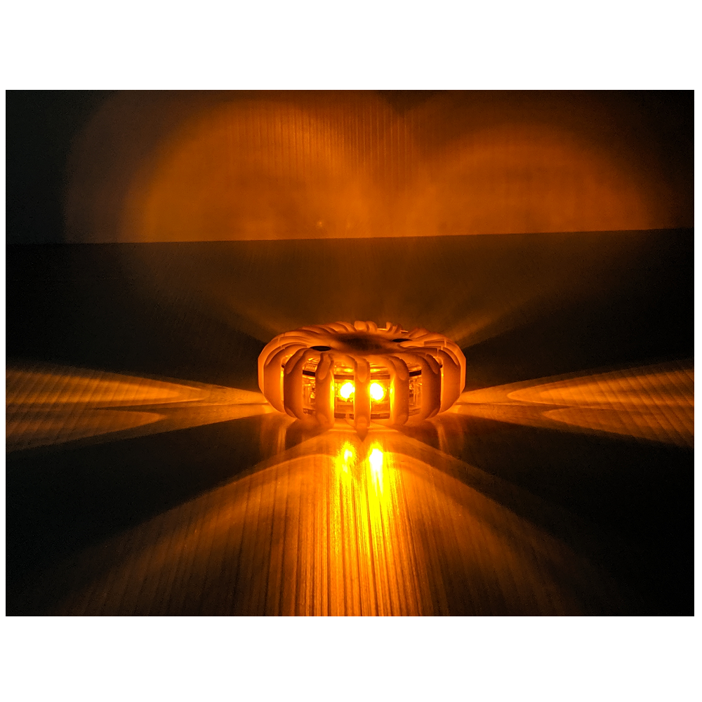A single LEO orange LED safety flare placed on a flat surface, showing a powerful 360-degree horizontal light beam pattern for emergency visibility.