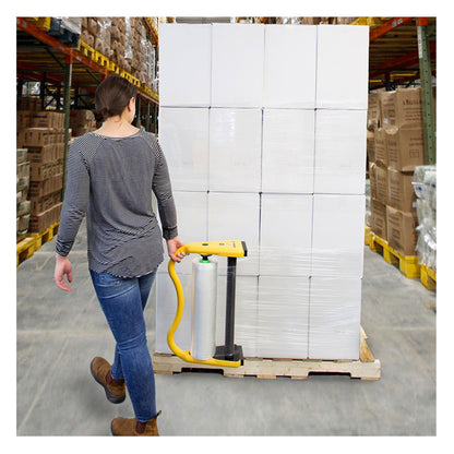 A warehouse worker using the yellow Precision Wrap XL hand dispenser to apply clear stretch film to a large pallet of white commercial boxes