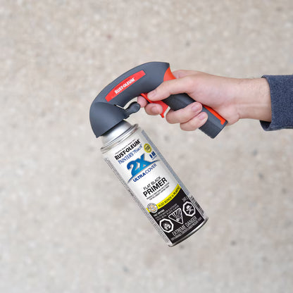 Hand holding a Rust-Oleum flat black primer aerosol spray can with an ergonomic black and red Comfort Grip spray trigger handle attached.