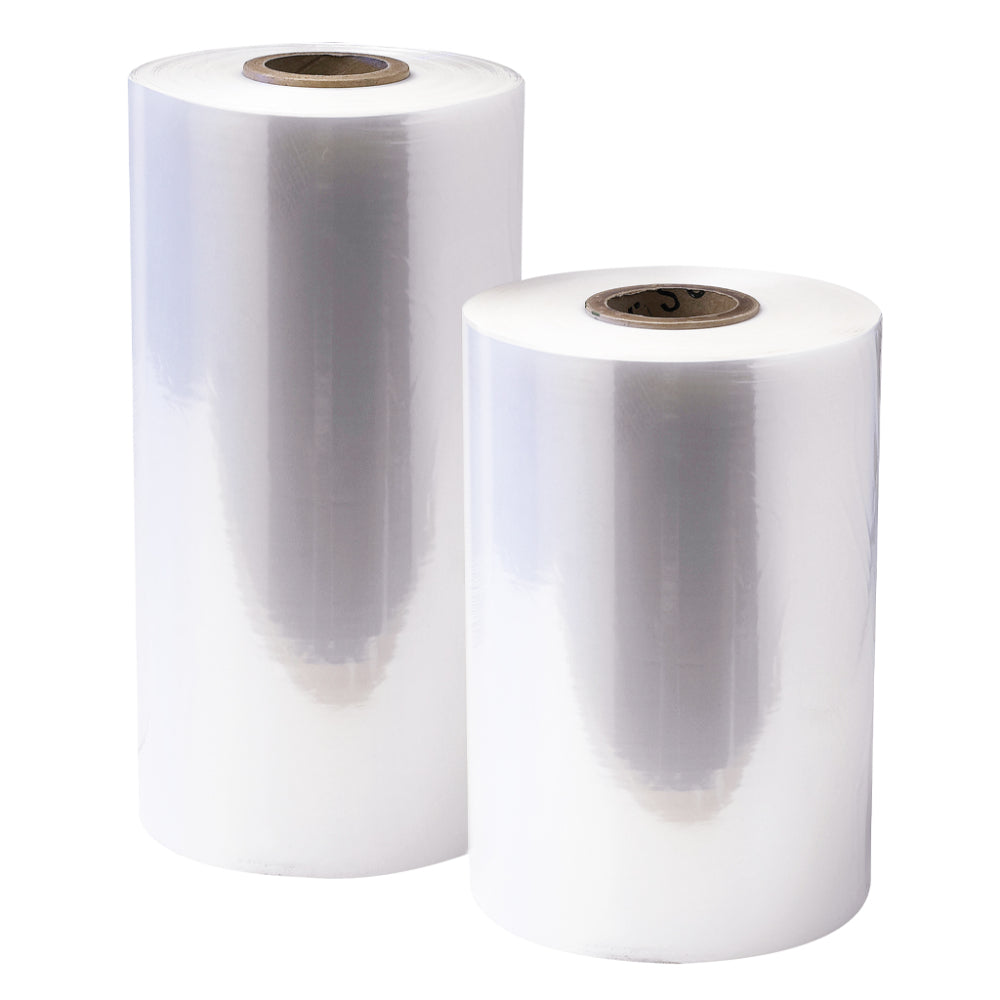 Two standing vertical rolls of clear perforated polyolefin shrink film wrap in varying heights with cardboard inner cores isolated on a white background
