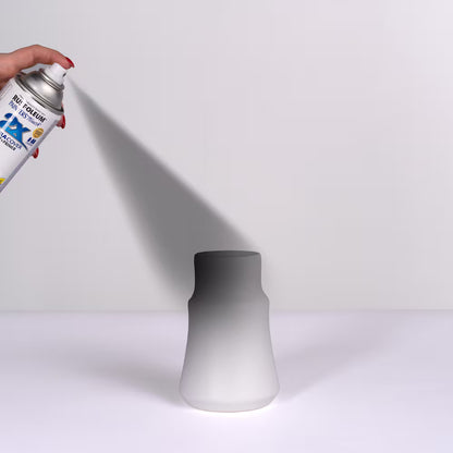 Close-up of a hand applying a smooth coat of flat black primer onto a white ceramic vase using a Rust-Oleum spray can.
