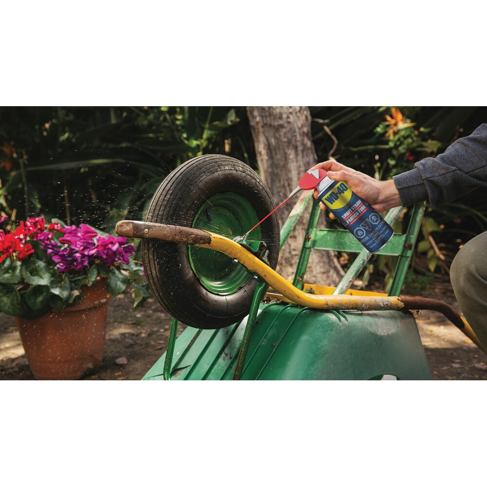 WD-40 Multi-Use Product with Smart Straw being applied to a wheelbarrow axle for lubrication.