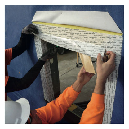 Detailed view of installers using Wigluv 20/40 window flashing tape with a 20/40mm split-release liner to create a precise, airtight seal in a window corner.