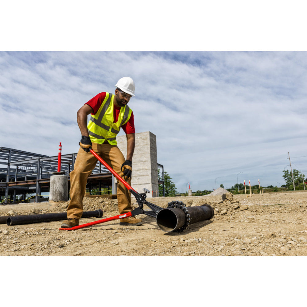 Construction worker in a white hard hat and safety vest carrying a RIDGID 286 soil pipe cutter over his shoulder at a job site.